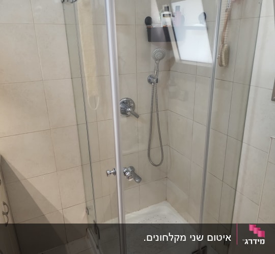 מקלחון זכוכית פינתי שקוף מותקן על אגנית בחדר רחצה